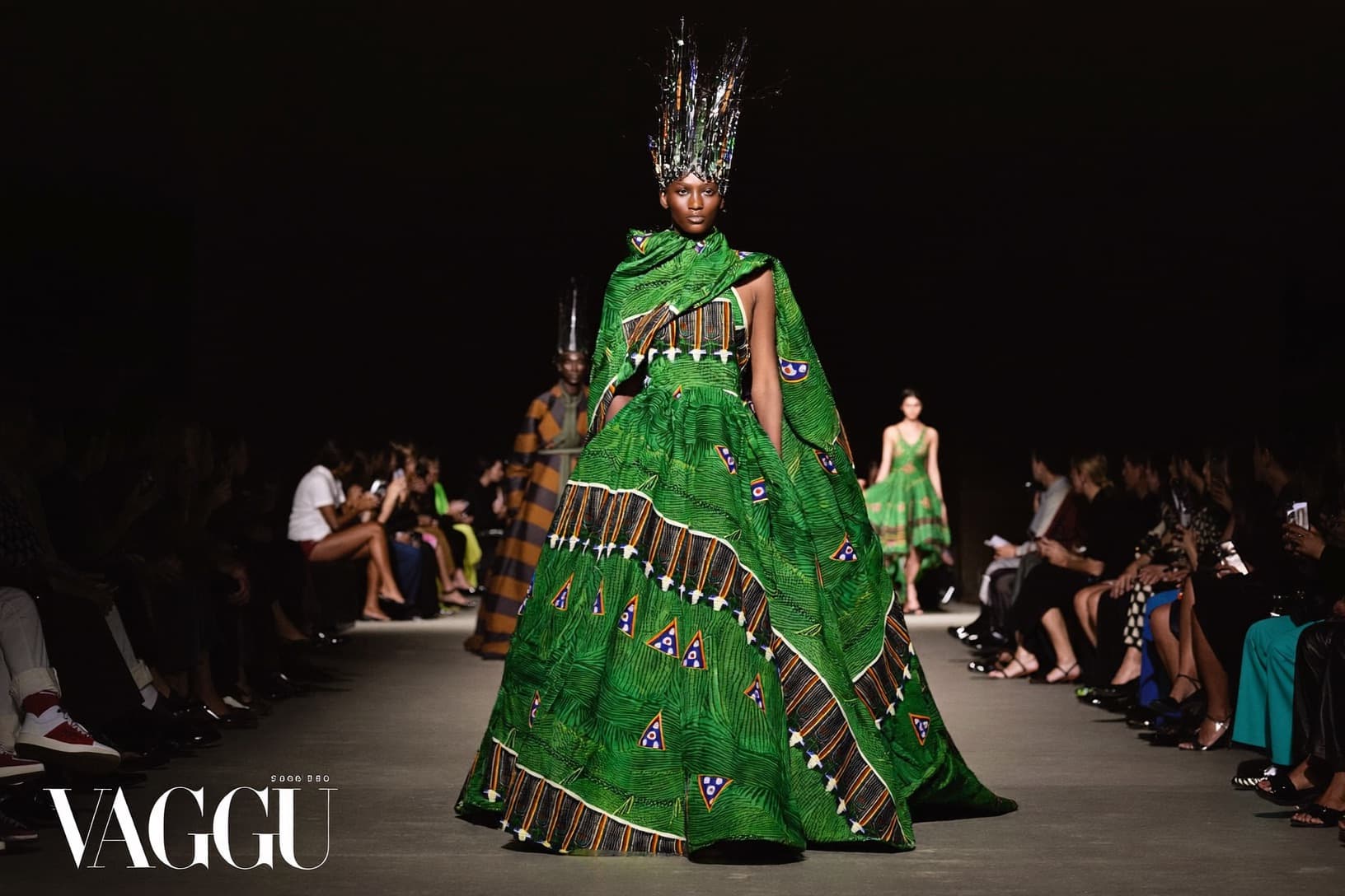A model in an emerald Ankara gown mid-stride on the runway