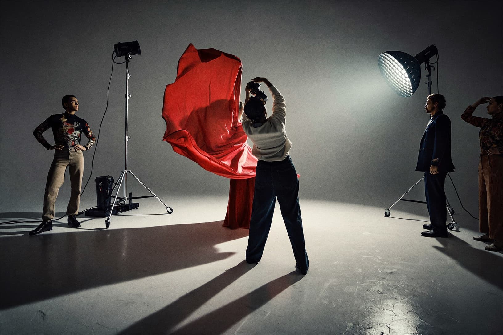 A model in a red gown under studio lights during a photo shoot