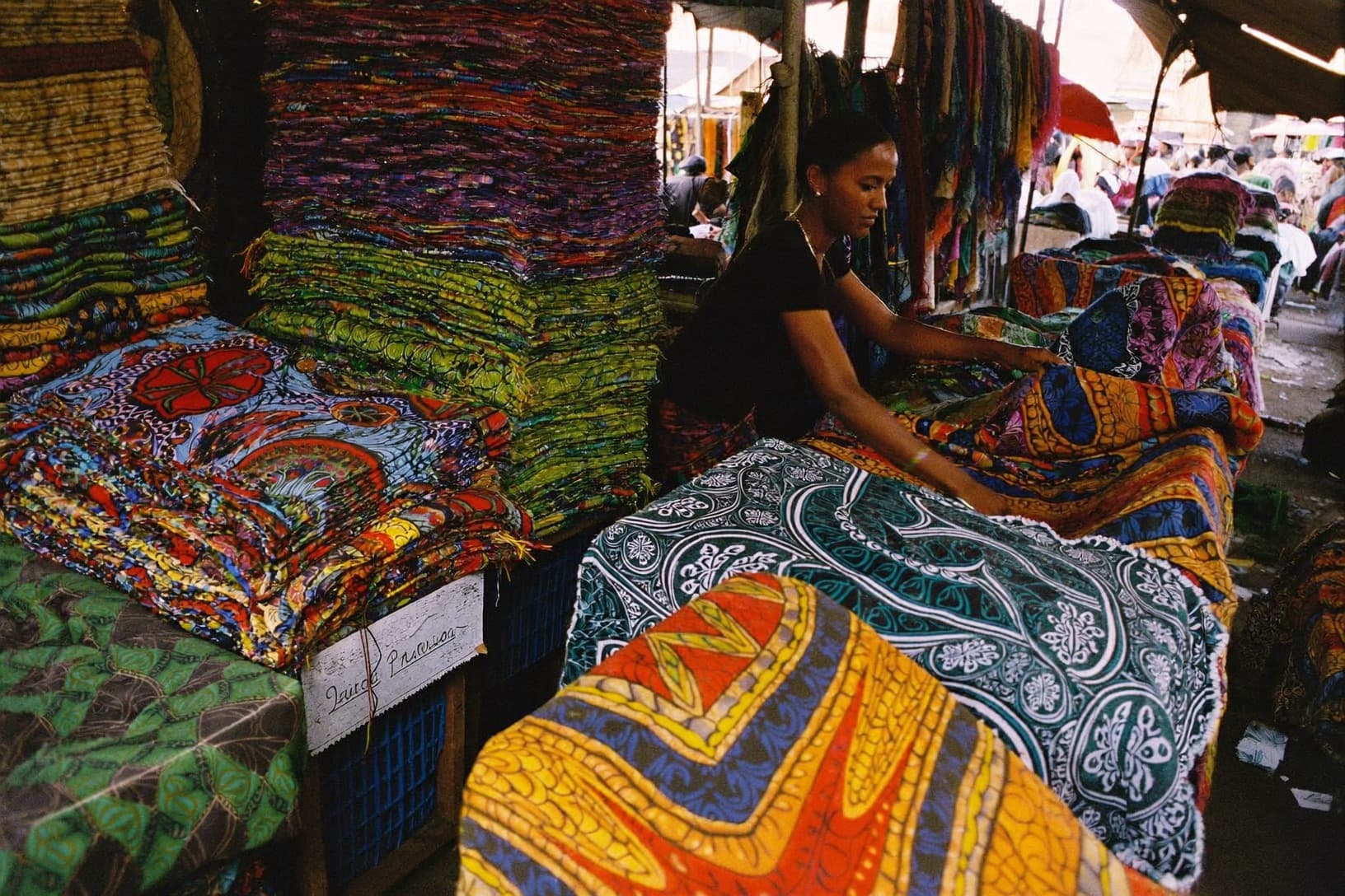 Bolts of wax-print fabric stacked at a market stall